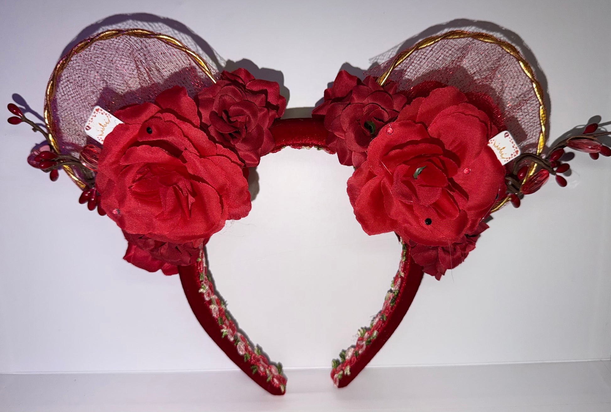 Red floral mouse ear headband with gold accents on a white background